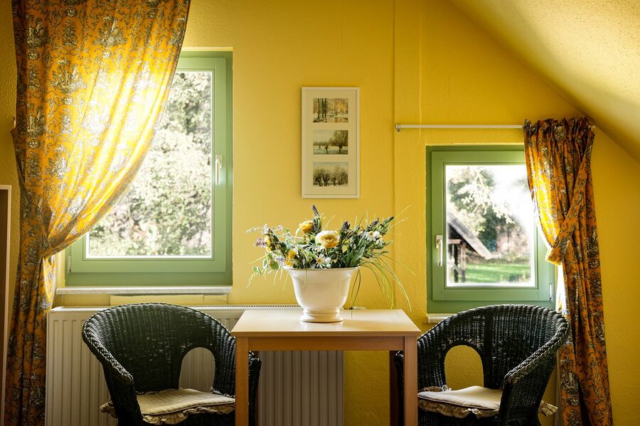 Sitzecke am Fenster mit Korbstühlen, Tisch und Blumenstrauß